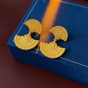 Vue détaillée de boucles d'oreilles vintage en forme d'éventail doré texturé