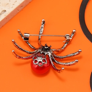 Vintage spider brooch with red bead and metallic texture on vivid orange background