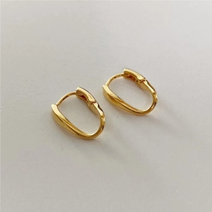 Detail of twisted gold metal hoop earrings with a minimalist polished surface