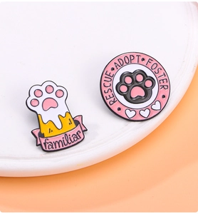 Detailed shot of enamel pet rescue pins with rescue adopt foster text on a ceramic tray