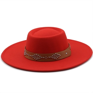 Detail of red wool fedora featuring a brown leather band with silver metal rivets
