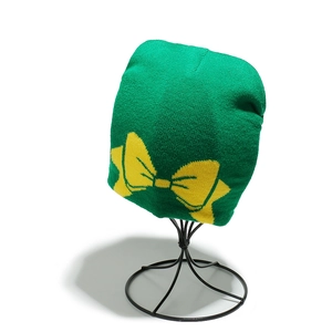 Détail d'un bonnet en tricot vert émeraude avec un motif de nœud jaune tissé serré