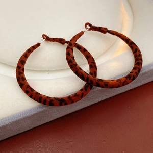 Gros plan de boucles d'oreilles rondes à imprimé léopard marron et texture floquée