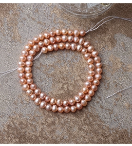 Macro shot of natural pink freshwater pearls strands on light brown frosted texture