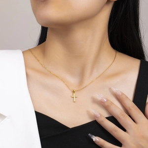 Close-up of a gold cross pendant necklace with sparkling white crystals on a model