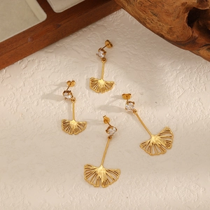 Elegant gold ginkgo leaf stud earrings with zircon stones on a rustic wooden tray
