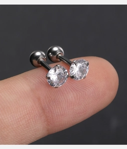 Vue détaillée de boucles d'oreilles argentées à vis avec zircon sur le bout du doigt
