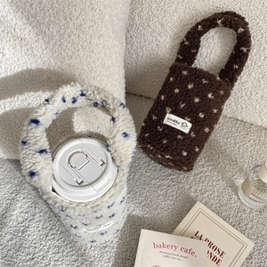 Detail of plush heart-themed coffee sleeves in white and brown with soft lamb wool texture