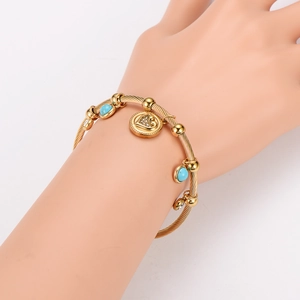 Gold twisted stainless steel bracelet featuring heart charm and turquoise stone inlay