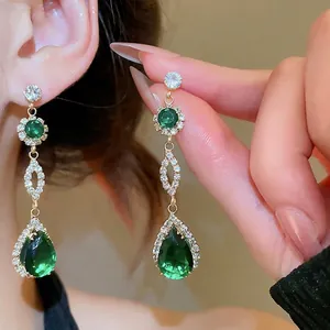 Elegant gold drop earrings with emerald green crystals and sparkling cubic zirconia pavé