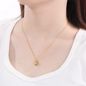 Close-up of a polished golden heart pendant necklace worn on a model's neck