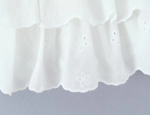 Close-up of white floral embroidery and hollow-out lace layers on the skirt hem