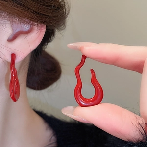 Detailed view of red flame gourd earrings with glossy enamel finish on a model