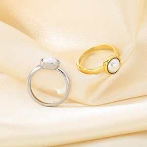 Detailansicht der gold- und silbernen Ringe mit Perle auf champagnerfarbenem Satinstoff