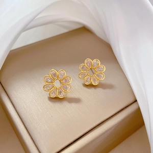 Detailed macro view of gold-plated daisy stud earrings with sparkling clear crystals