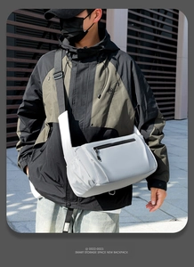 Detail showing the light grey waterproof nylon crossbody bag with black zipper pockets