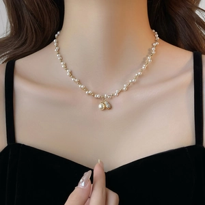 Elegant pearl and gold bead necklace with sparkling pendants on a female model