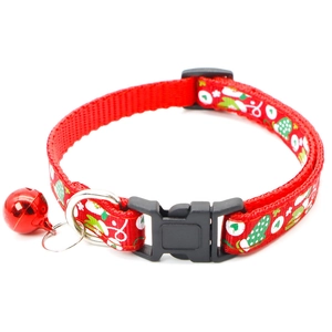 Detail of red fabric pet collar featuring apple patterns, plastic buckle, and metal bell