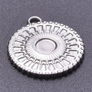 Detailed macro view of a silver stainless steel circular pendant with sunburst texture