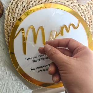 Detail of peeling film from Mother's Day acrylic plaque with golden Mom lettering