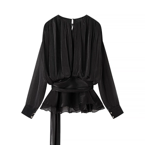 Détail du haut en satin noir cintré avec ourlet à volants et boutons de manchette métalliques