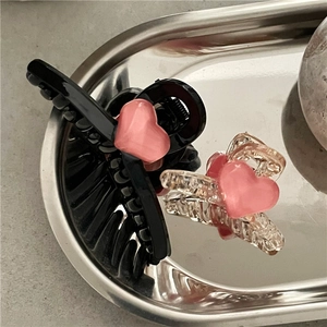 Close-up of pink heart mini hair clips in black and transparent plastic on metal tray