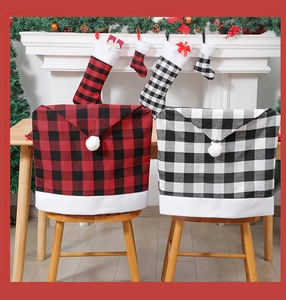 Detail of red and black buffalo plaid Christmas chair covers with white pom-poms in a cozy room