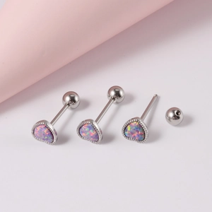 Macro de piercings de langue en forme de cœur avec opale irisée sur un support rose doux