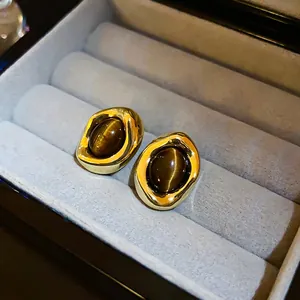 Retro gold plated tiger eye stud earrings with irregular wave design in a jewelry box