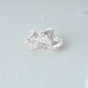 Macro shot of S925 sterling silver wavy hoop earrings with pave cubic zirconia stones