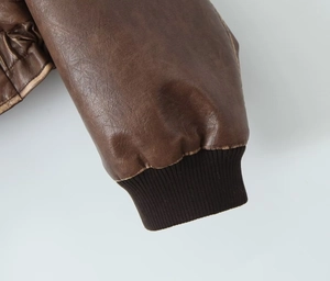 Détail de la manche d'une veste en similicuir marron avec poignets en tricot côtelé