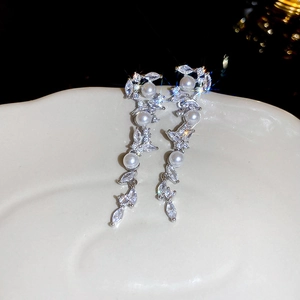 Detail view of silver tassel earrings with white pearls and sparkling zircons on a white base