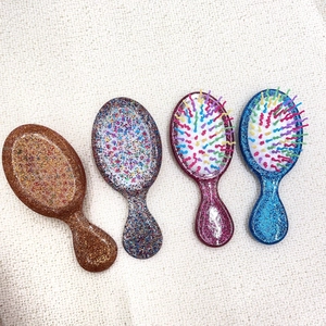 Top view of mini glitter air cushion hairbrushes in pink blue silver and brown