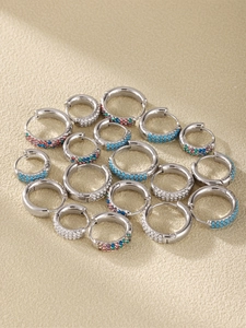 Detailed view of silver hoop earrings with blue, white, and colorful inlaid crystals