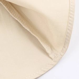 Detail shot of the reinforced seams and edging craftsmanship on beige fabric dress