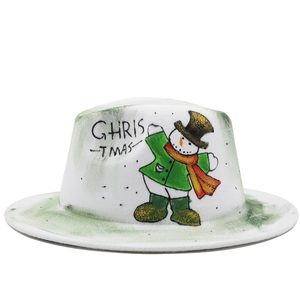 Détail d'un chapeau en laine blanche avec bonhomme de neige peint et texte de Noël