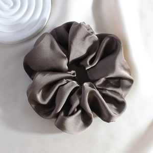 Macro shot of dark grey satin scrunchie featuring elegant silky sheen on soft fabric