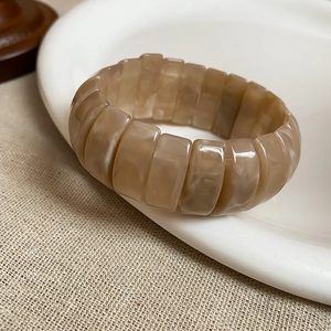 Close-up of marble-textured resin elastic bracelet with brown rectangular beads