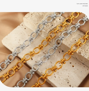 Detailed close-up of gold and silver oval link chains with sphere accents on silk fabric