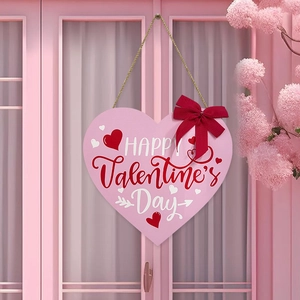 Pink heart-shaped wooden Happy Valentine's Day sign with a red bow on a pink door
