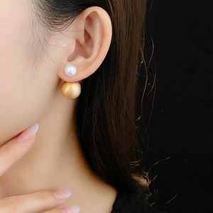 Close-up of elegant double pearl stud earrings with gold brushed finish on female model