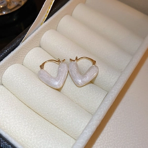 Detail view of gold-plated V-shaped pearl stud earrings in a luxury jewelry box
