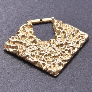 Macro detail of 18k gold plated stainless steel rhombus pendant with hammered texture