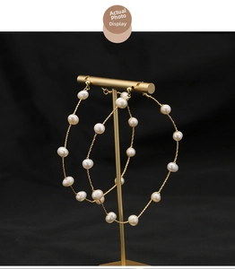 Macro detail of handmade 18K gold plated hoop earrings featuring woven white pearls