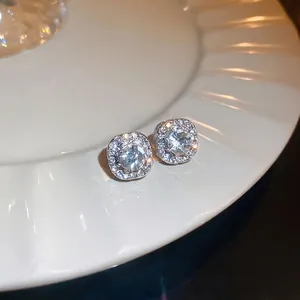 Elegant square halo stud earrings with sparkling crystals on a textured white plate