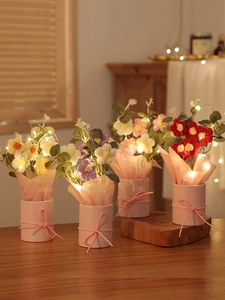 Detail of four handmade crochet flower bouquets in pots with LED lights and pink bows