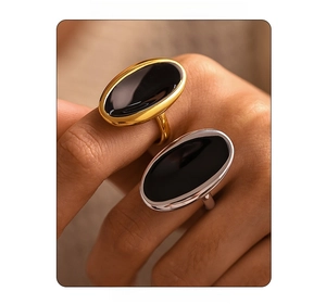 Detailed close-up of oval black enamel rings in gold and silver finish on a hand
