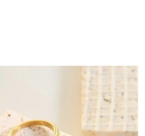 Nahaufnahme eines minimalistischen klobigen Goldrings auf Natursteinoberfläche