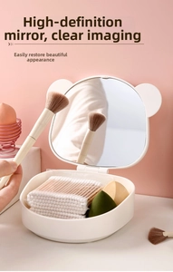 Detail of bear-eared folding vanity mirror with storage base holding makeup sponges