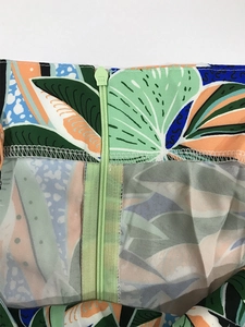 Detail of tropical print fabric featuring a light green invisible zipper and stitching